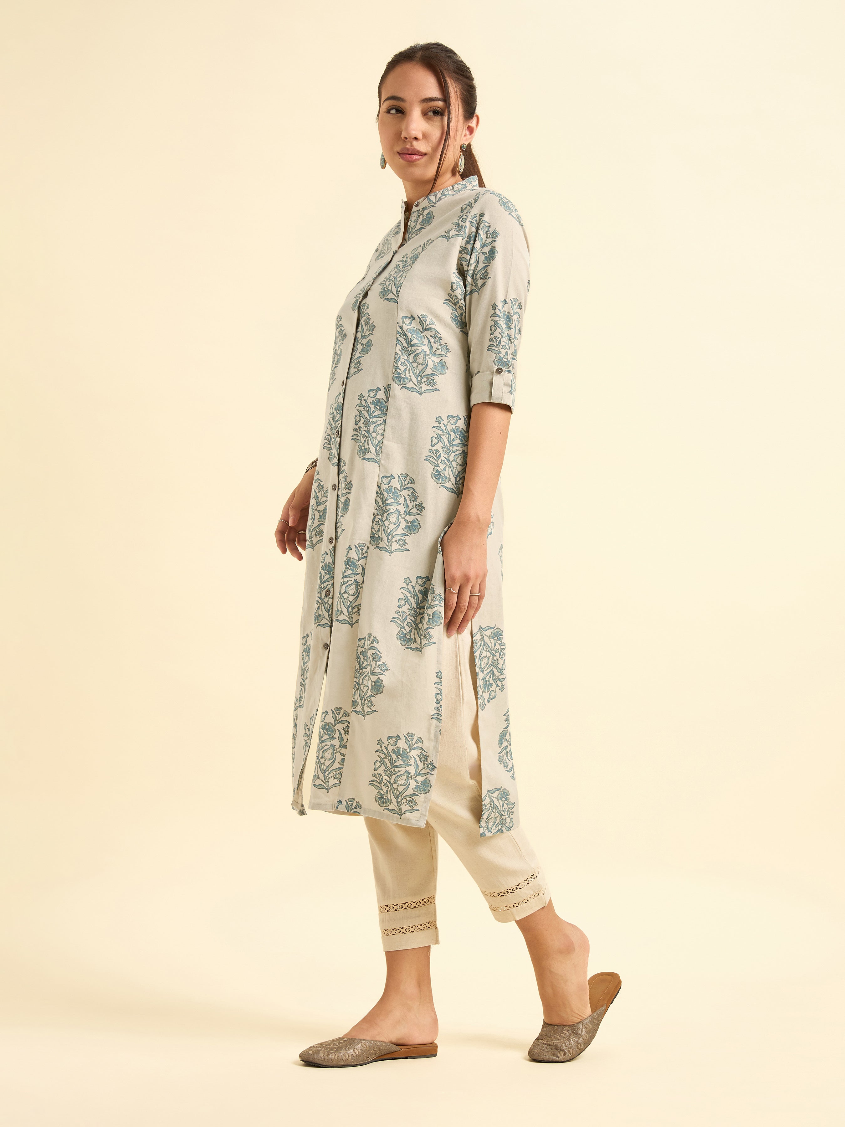 Woman wearing a floral printed kurta with beige pants on a beige background