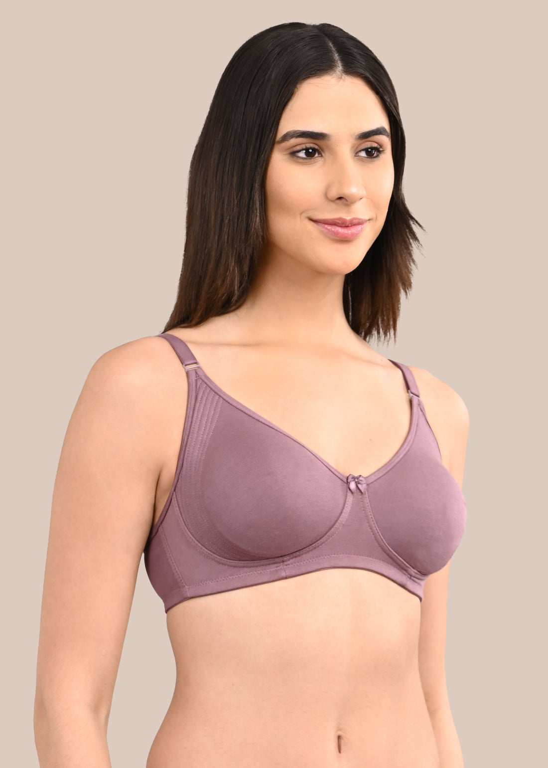 Woman wearing a bra against a neutral background