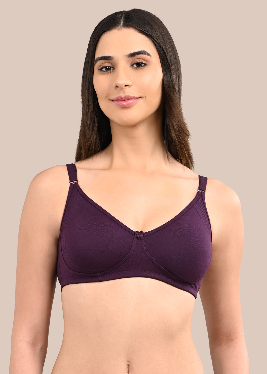 Woman wearing a bra against a neutral background